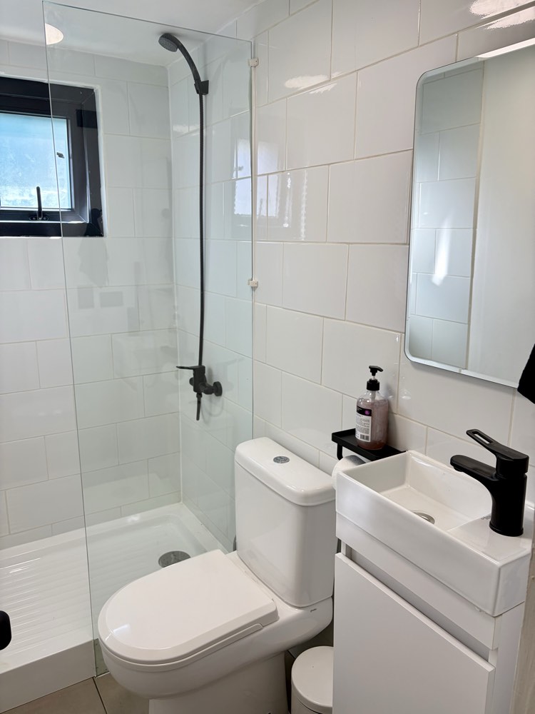 Baño de Espacio Montt, ducha con separación de vidrio y grifería negra